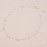 Delicate gold-tone necklace featuring twelve evenly spaced bezel-set sparkling stones along a fine chain, offering a dainty and radiant look