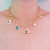 Chunky gold-link necklace featuring a mix of whimsical charms including an angel, rose, and gem accents—blending vintage elegance with romantic flair.