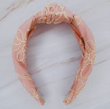 A solid-color knotted headband accented with subtle white stitching for a simple yet refined look.