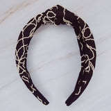 A solid-color knotted headband accented with subtle white stitching for a simple yet refined look.
