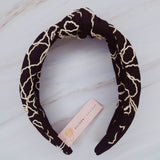 A solid-color knotted headband accented with subtle white stitching for a simple yet refined look.