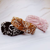 A solid-color knotted headband accented with subtle white stitching for a simple yet refined look.