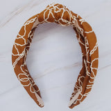 A solid-color knotted headband accented with subtle white stitching for a simple yet refined look.