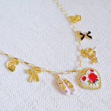 Gold-tone charm necklace featuring a dreamy mix of rose, ballet shoe, angel, and swan charms—blending grace, romance, and whimsy into a delicate statement piece.