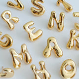 Glossy, balloon-style metal initial brooch pins in a playful, rounded design, available in multiple letters with a puffy, dimensional shape and metallic finish.