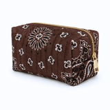 a quilted bandana print cosmetic case in brown with gold zipper on white background