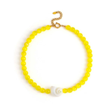 Yellow beaded necklace with a white shell pendant on a white background