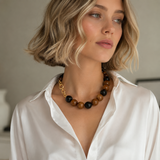 Woman wearing a white shirt and a necklace with black and brown beads.
