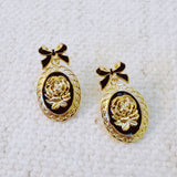 Antique-inspired black and gold drop earrings featuring an ornate cameo profile framed in gold with delicate bow-shaped top accents