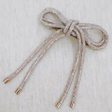Hair clip featuring a sparkly tube-style bow embellished with rhinestones, perfect for adding a touch of glam to any hairstyle.