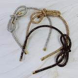 Set of three beaded headbands in silver, gold, and black on a marble surface.