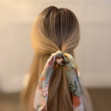 Trio of scarf hair scrunchies with colorful blooming floral patterns and soft, flowing ribbons—ideal for adding a lively, festival-ready touch to any look.