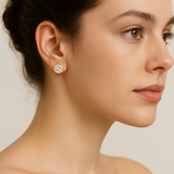 Close-up of a woman wearing gold earrings with a clear gemstone against a neutral background