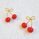 Playful gold-tone earrings featuring a bow and cherry design, adding a whimsical and charming touch to your style.