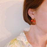 Playful gold-tone earrings featuring a bow and cherry design, adding a whimsical and charming touch to your style.