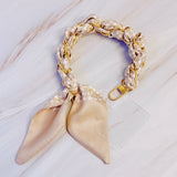 Stylish braided scarf lanyard featuring a gold-tone chain intertwined with patterned fabric, designed to securely attach to a phone while doubling as a chic fashion accessory.