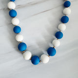 Necklace with blue and white beads on a light gray background