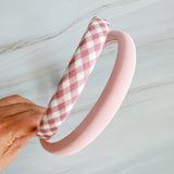 A set of padded fabric headbands in assorted pastel and plaid designs, including soft pink, green tones. Each headband features a cushioned, textured surface that blends solid and patterned fabrics for a stylish, comfortable everyday accessory.