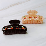 A set of two hair claws featuring a row of vibrant red cherry designs, adding a playful and fruity touch to any hairstyle.
