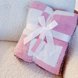 Soft pink and white checkered blanket featuring a vibrant cherry cluster with a pink bow detail, perfect for adding a pop of fun and cozy charm to any space.