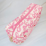Rectangular cosmetic case featuring an all-over cherry and bow print with a top handle, perfect for everyday storage of beauty essentials.