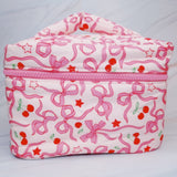Travel-friendly cosmetic case with top handle, featuring a charming cherry and bow print, ideal for organizing beauty essentials on the go.