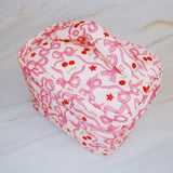 Travel-friendly cosmetic case with top handle, featuring a charming cherry and bow print, ideal for organizing beauty essentials on the go.