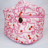 Travel-friendly cosmetic case with top handle, featuring a charming cherry and bow print, ideal for organizing beauty essentials on the go.