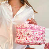 Travel-friendly cosmetic case with top handle, featuring a charming cherry and bow print, ideal for organizing beauty essentials on the go.