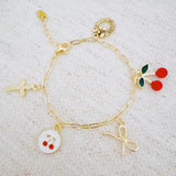 Gold bracelet with cherry, cross, and bow charms– playful Y2K accessory