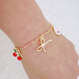 Gold bracelet with cherry, cross, and bow charms– playful Y2K accessory