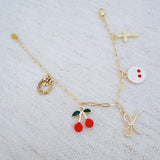 Gold bracelet with cherry, cross, and bow charms– playful Y2K accessory