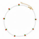 Necklace with white beads and red and green floral accents on a white background