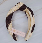 Knotted headband with bold black stripes on a beige background for a chic and modern look.