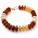 A beaded necklace featuring translucent amber and honey-colored oval beads alternating with smooth, matte off-white disc beads, finished with a gold-tone clasp on a white background.