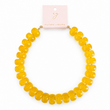 Yellow necklace on a white background with a pink card displaying 'eg' branding.