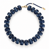 A beaded necklace made of polished sapphire navy disc beads with a small gold clasp and extender chain, photographed on a clean white background.