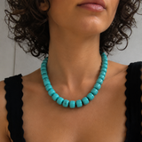 Woman wearing a turquoise beaded necklace against a neutral background