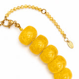 Yellow beaded bracelet with gold clasp on a white background