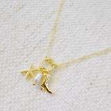 Gold-tone chain necklace adorned with a starfish charm and a western boot charm, capturing a playful blend of coastal and cowgirl vibes.