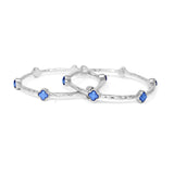 Silver bangle with blue star-shaped stones on a white background