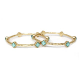 Gold bangles with turquoise stones on a white background. Slim gold bangle bracelet featuring small clover-shaped station accents along the band, available in multiple color variations for a delicate, stackable look.