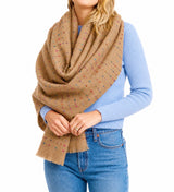 Person wearing a brown patterned scarf, blue sweater, and jeans on a white background