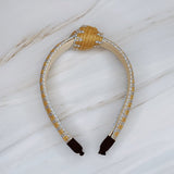 Raffia headband with vibrant color-stitched detail in a knotted design, offering a fun and summery look.
