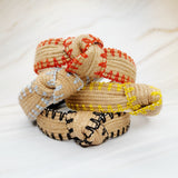 Raffia headband with vibrant color-stitched detail in a knotted design, offering a fun and summery look.