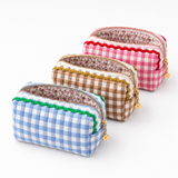 blue, pink, brown gingham fabric with colorful wavy details on top lined up, zipper all opened showing floral lining.