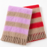 Two striped fuzzy scarves with fringe, one in lavender and beige stripes and the other in red and beige stripes, displayed on a clean white background.