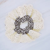 Stylish hair scrunchie featuring a bold cheetah print with delicate crochet trim, blending wild flair with a touch of handcrafted charm.