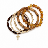 Stack of beaded bracelets with a cross charm on a white background