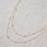Elegant layered necklace featuring delicate gold chains accented with crystal bezel stations, perfect for a subtle sparkle and refined style.